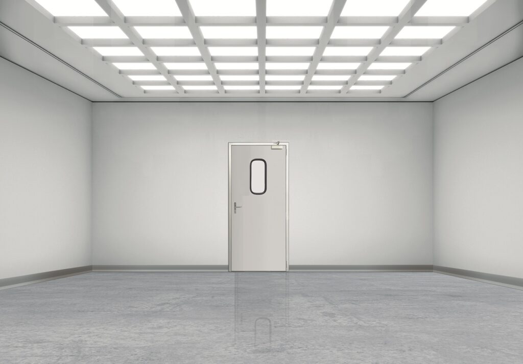 Empty white room with grid ceiling lights and a central door with window
