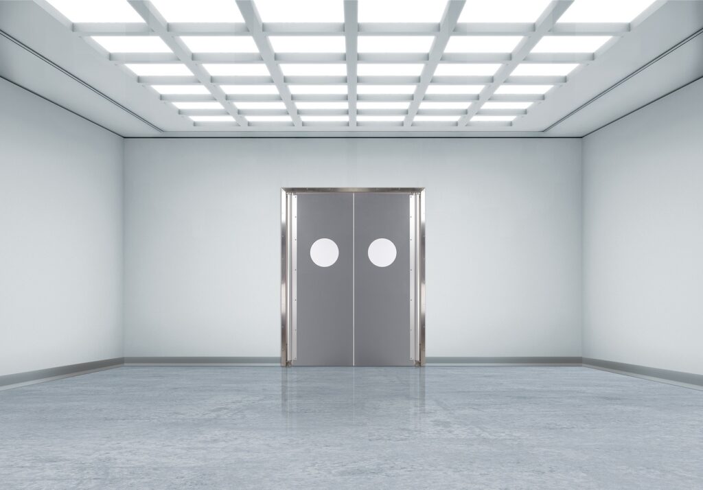 Bright, empty corridor with gray double doors and round porthole windows.