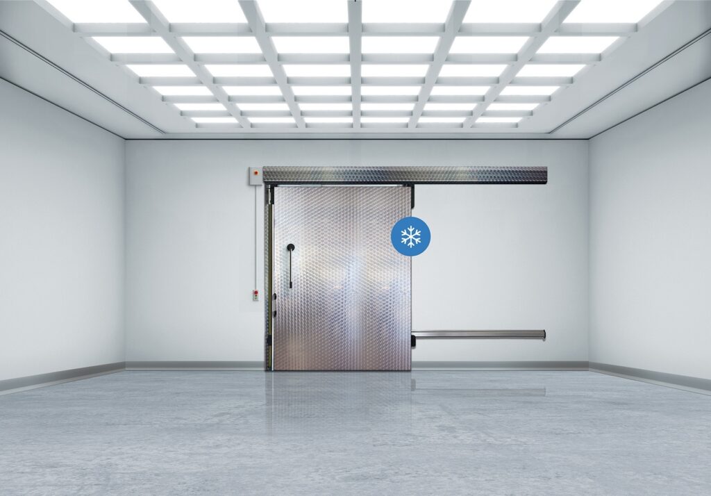 Empty industrial room with sliding metal freezer door, snowflake symbol