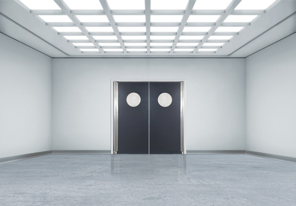Bright, minimalist room with black double swing doors featuring round windows.