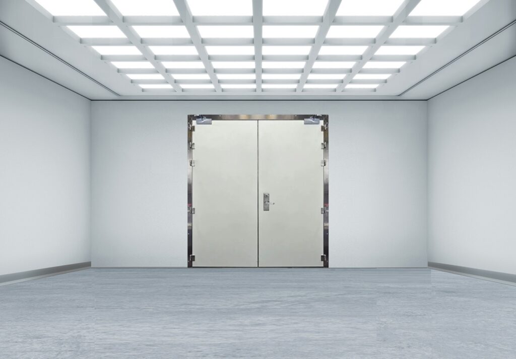 Bright, sterile room with grid ceiling lights and a central double metal door.